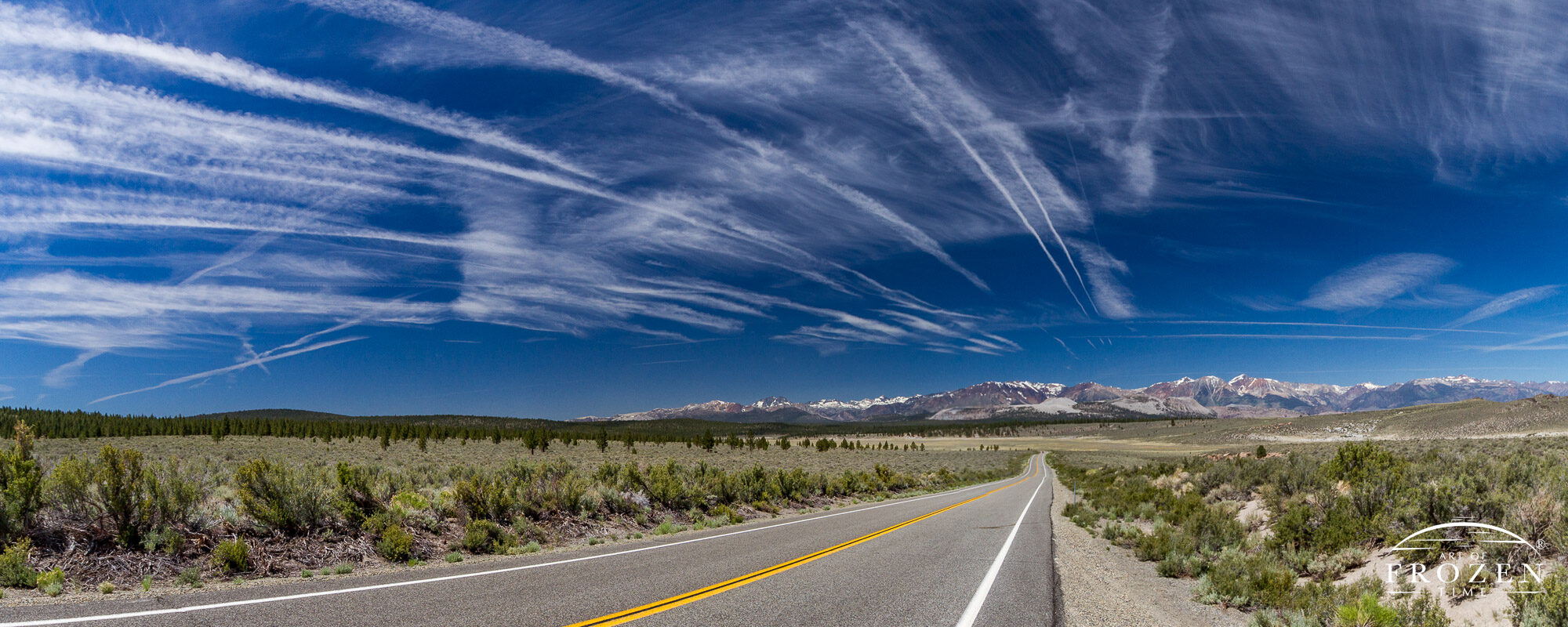 An infinite view to the eastern Sierra Nevada mountains where successive contrails moved laterally every few minutes in their airmass over a fixed road.