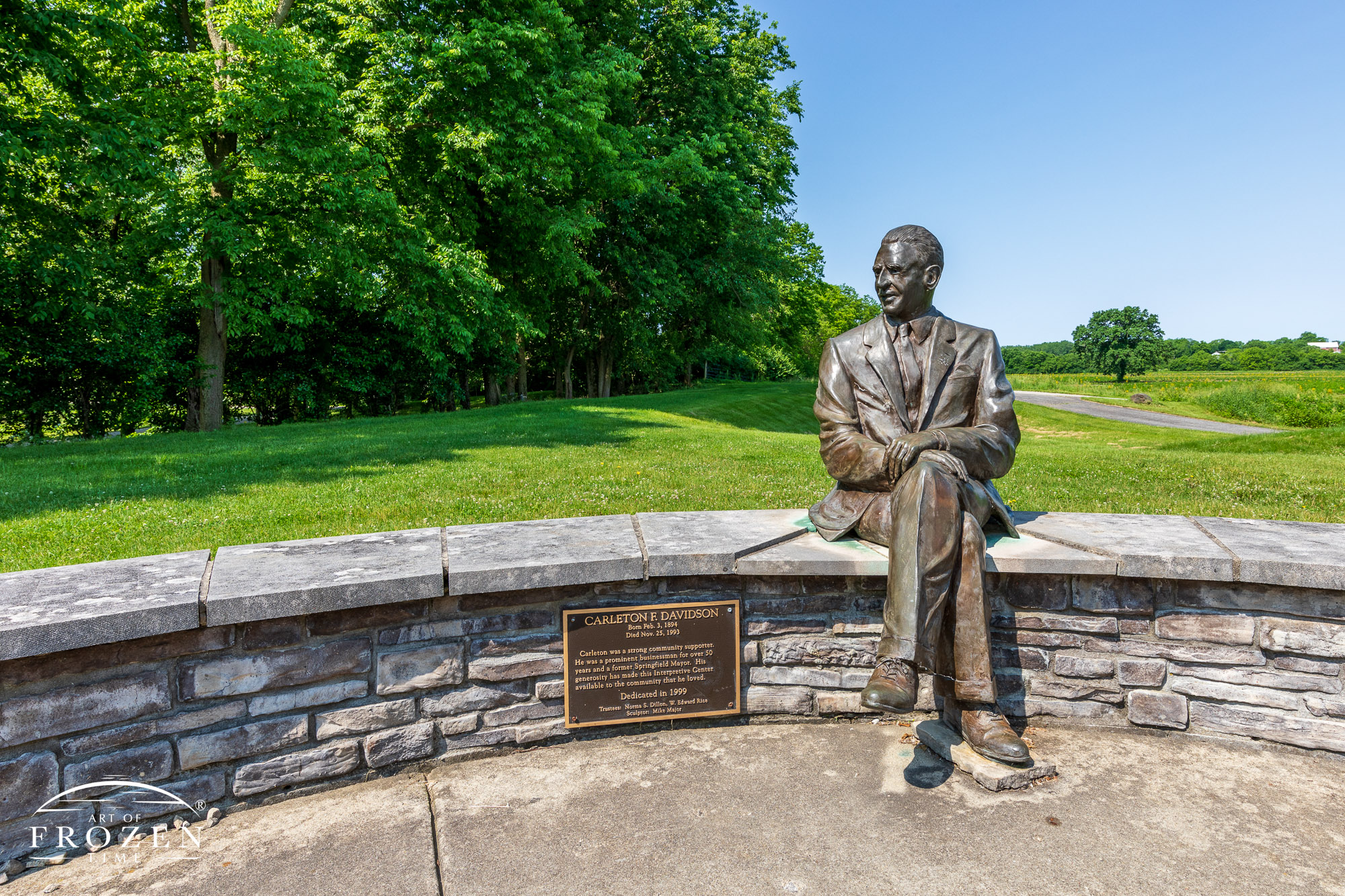 A bronze sculpture of Carleton F. Davidson sitting on a small wall which recognizes his contributions to Springfield Ohio.