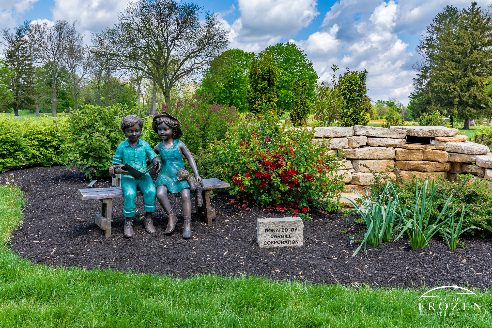 A view of the children’s waterfall feature features this bronze sculpture of a boy and girl reading a book while sitting on a bench