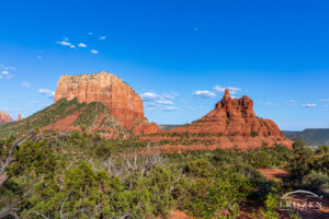 An evening view of Courthouse Butte and Bell Rock as the warm light illuminates the red sandstone under blue Arizona skies.