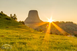 A sunset silhouette of Devils Tower National Monument before the sun sets behind the geologic formation