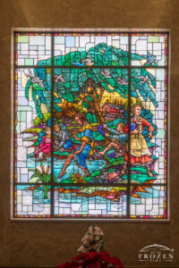 Historic stained-glass windows created by Louis Comfort Tiffany featuring his opalescent glass depicting a lady dipping her toe in the water as others sit along the shoreline