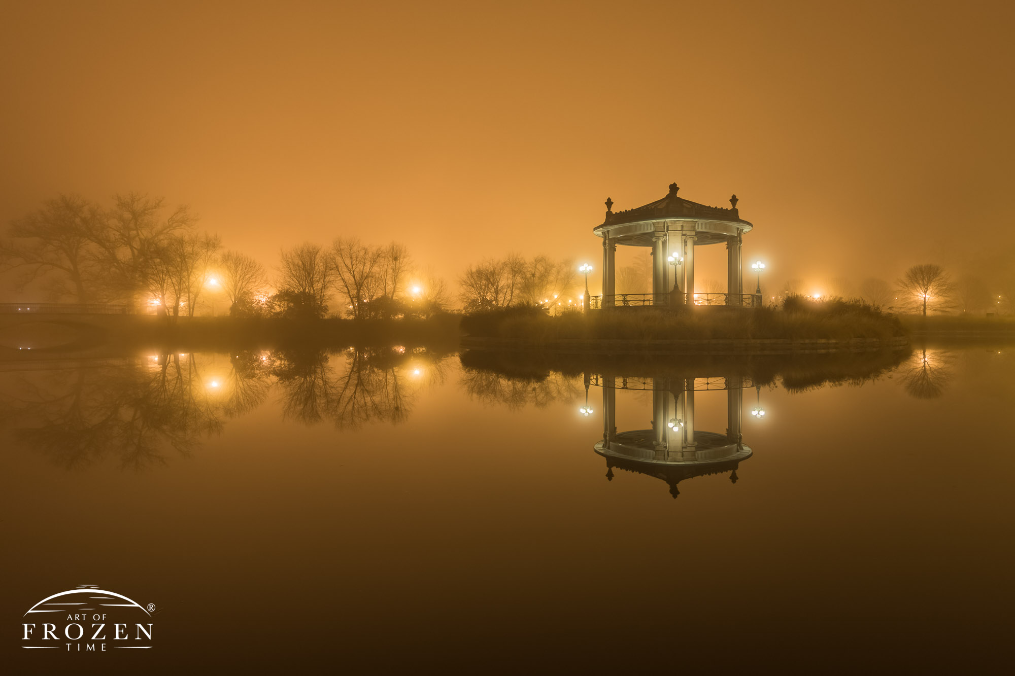 A nighttime heavy fog scene of St Louis Forest Park where parking lighting silhouettes the Nathan Frank Bandstand