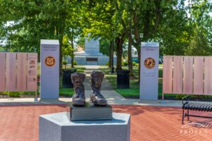 Bronze military boots at Fort Recovery Veterans Plaza in Ohio, resting on a granite history book near service medallions and veterans name panels.