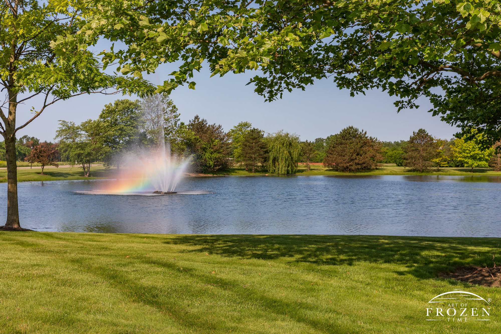 The spray from a fountain in a small lake refracts rainbow colors in the gentle summer breeze.