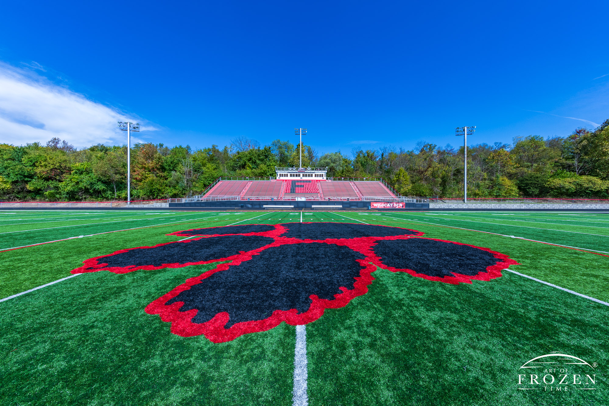 Mid field of the Franklin High School’s Wildcat stadium where the paw print logo occupies the foreground and the Franklin, Ohio bleachers in the distance