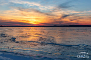 Lake ripples frozen in place during this deep winter freeze as the last warm light disappears over the western horizon.