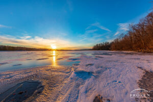 A frozen lake at sunset where the golden light rakes across the ice surfaces