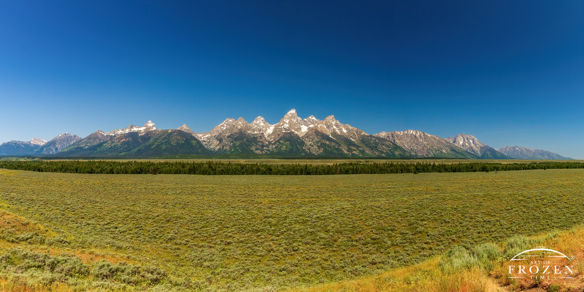A panorama of the Grand Tetons and their glaciers while a sagebrush plain and the Snake River fill the foreground
