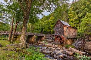 An enchanting West Virginia State Park scene where the Glade Creek Grist Mills stands in Glade Creek on a late summer evening as golden light paints the mill and surrounding trees