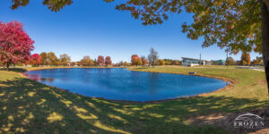 Panoramic image of the large pond at Edison State Community College surrounded by richly colored autumn leaves under a burning blue sky