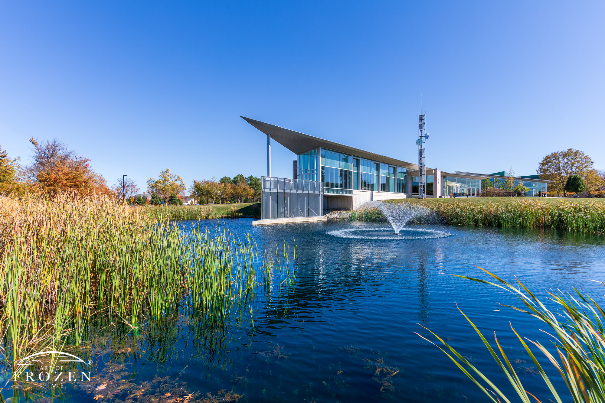 An architecturally pleasing building whose angular construction juts out over a small pond