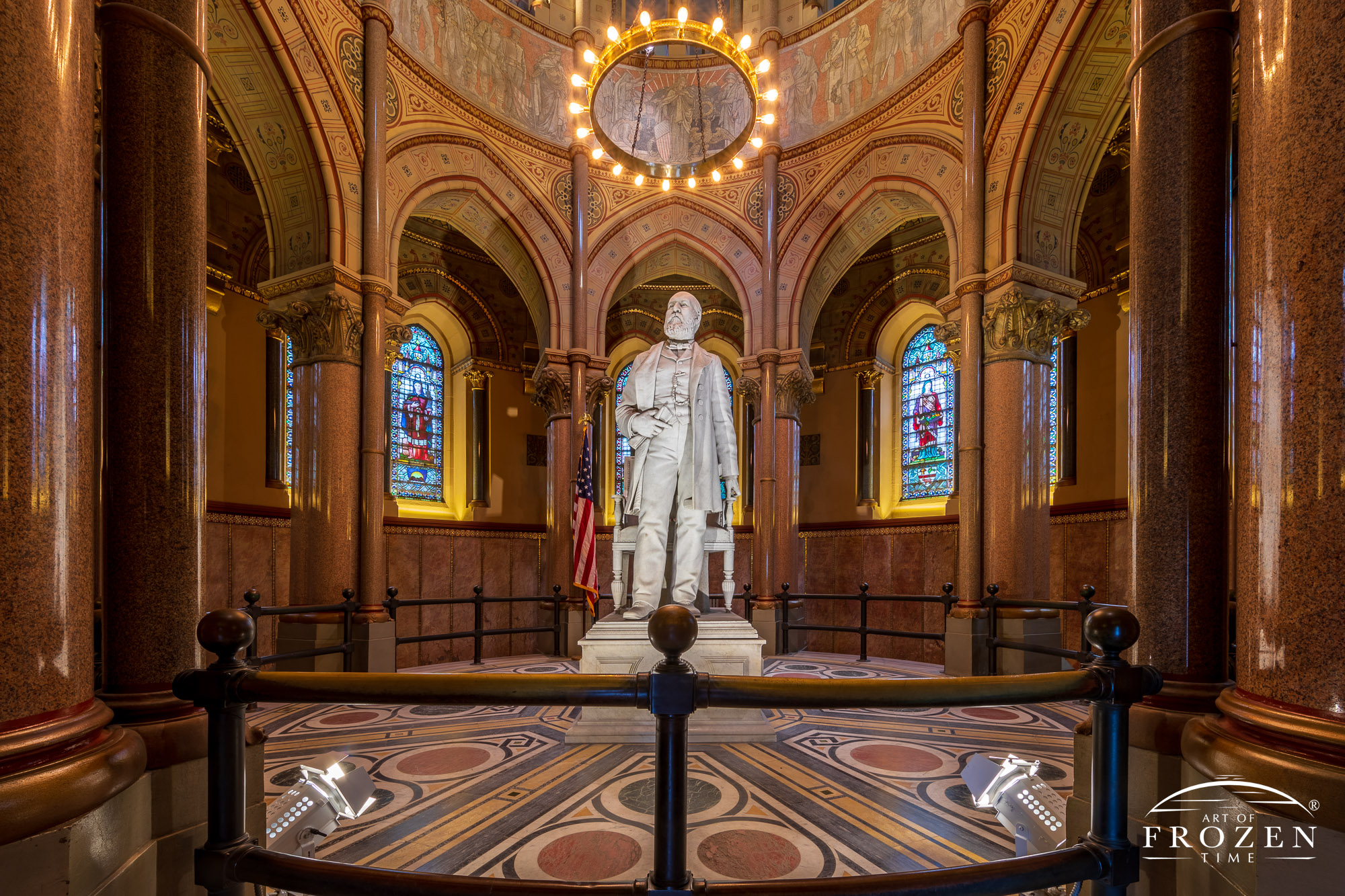 Upper chamber of President Garfield’s mausoleum where a white marble statue of the President stands in the midst of a rotunda with stained-glass windows.