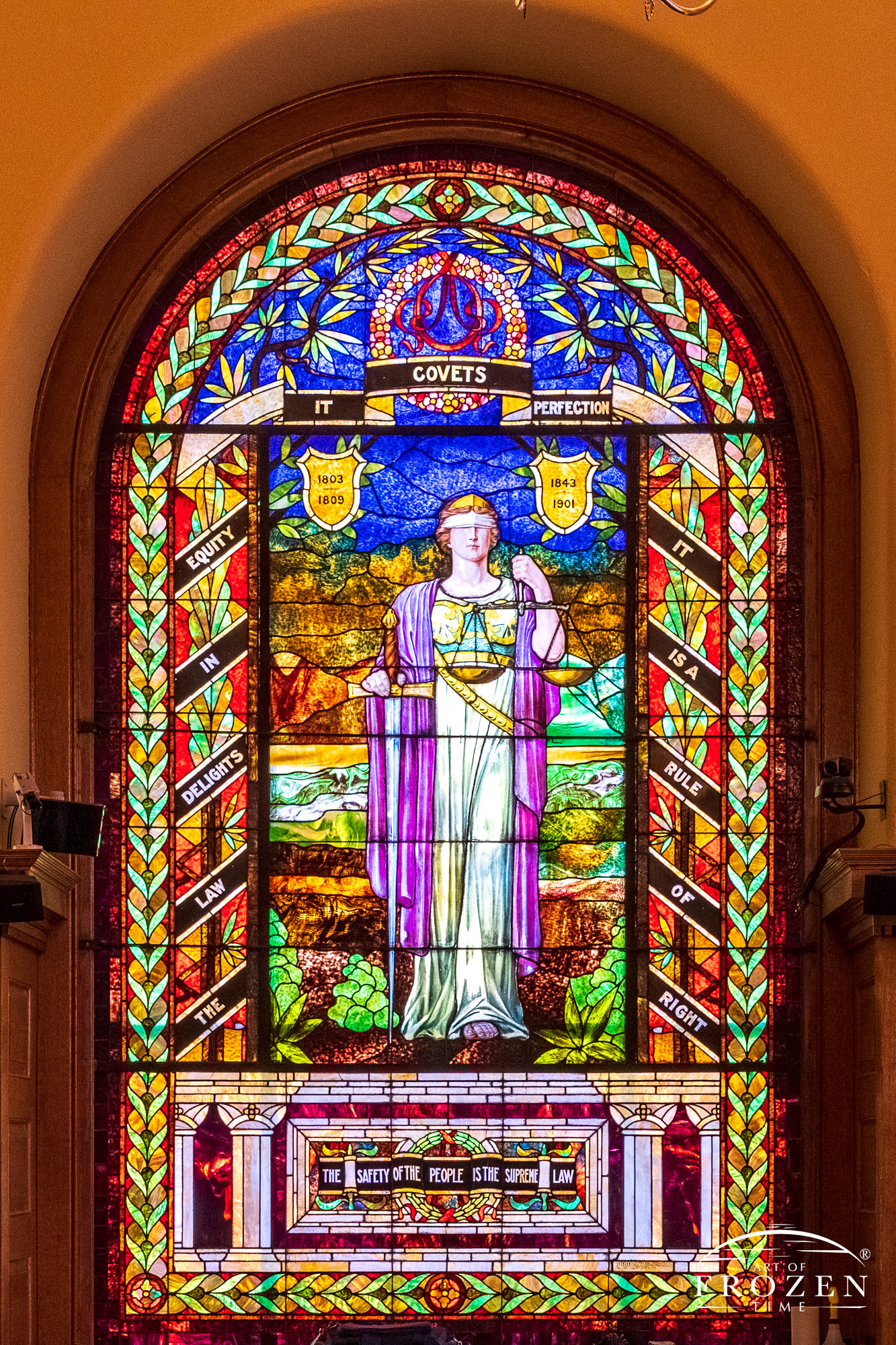 Stained-glass window featuring a blindfolded woman holding the scales of justice
