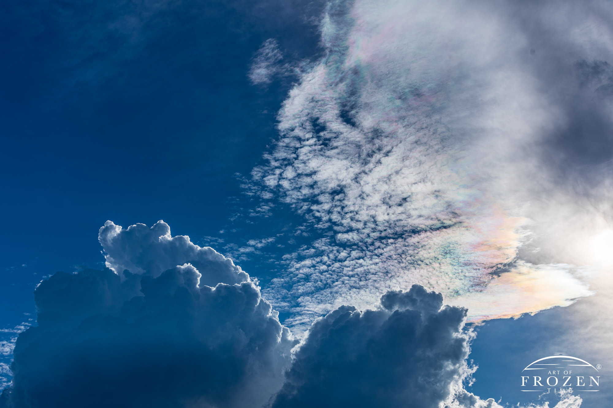 An interesting cloudscape where cirrus clouds refract light in colorful ways as lower rain clouds transition to thunderstorms.