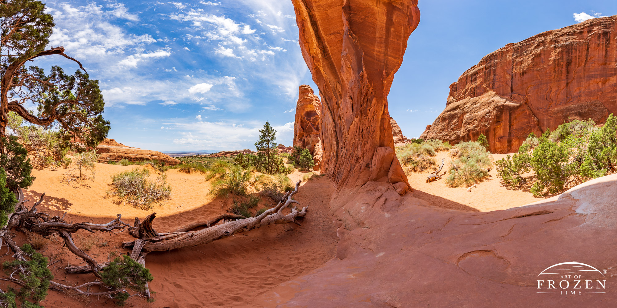 A panorama view of Pine Tree Arch from the base of the rock arch as wispy clouds pass overhead