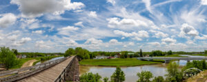 A bike trail bridge leading off into the distance as the Great Miami River flows by and the wispy clouds float overhead