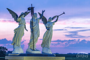 A ethereal twilight image of cement sculptures representing trumpet holding angels on Resurrection Day where the evening skies displaying blue and purples hues