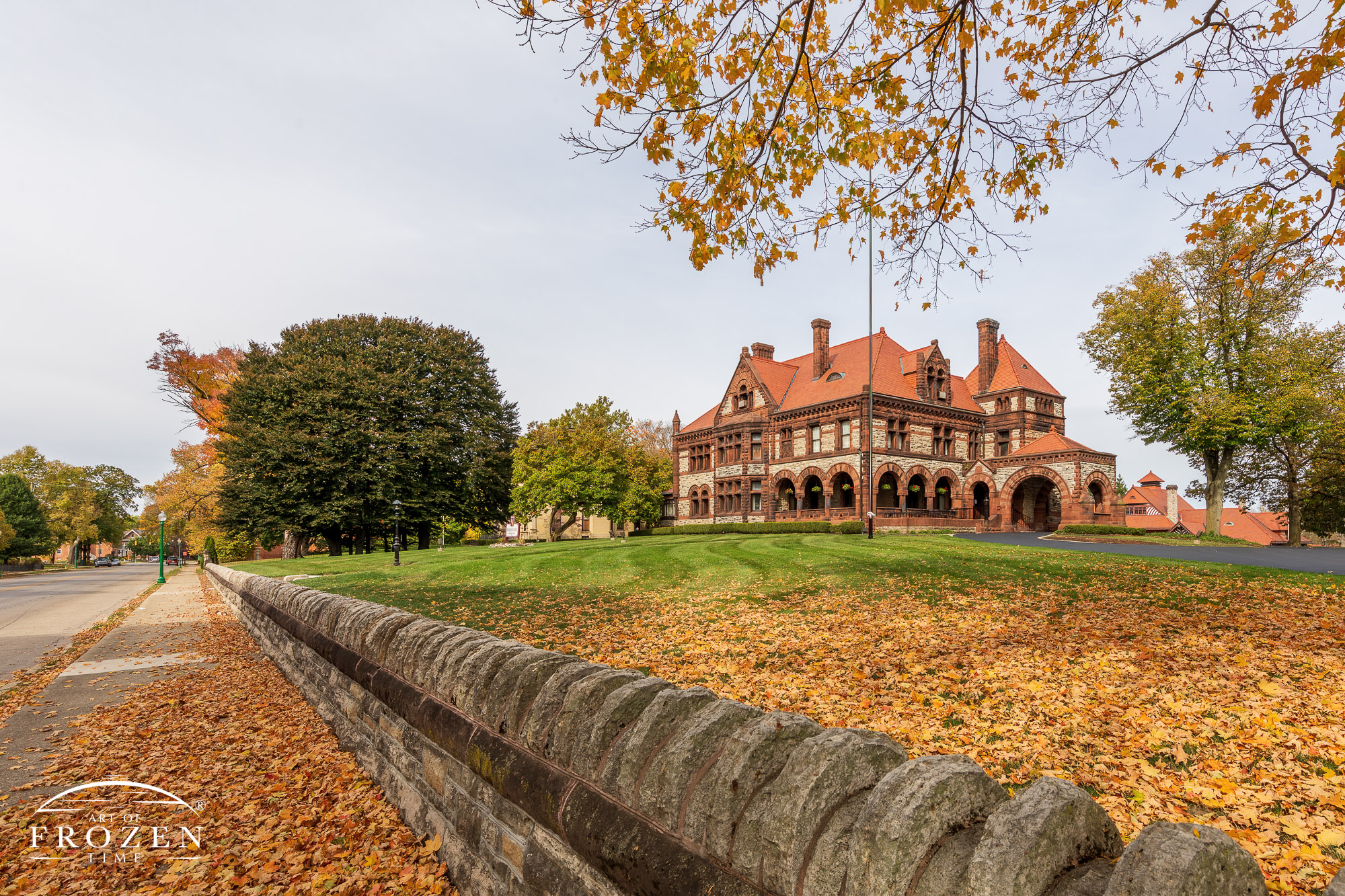 An outside view of a mansion in Springfield, Ohio, featuring Richardsonian Romanesque Architecture where autumn-colored trees match the home’s warm colors.