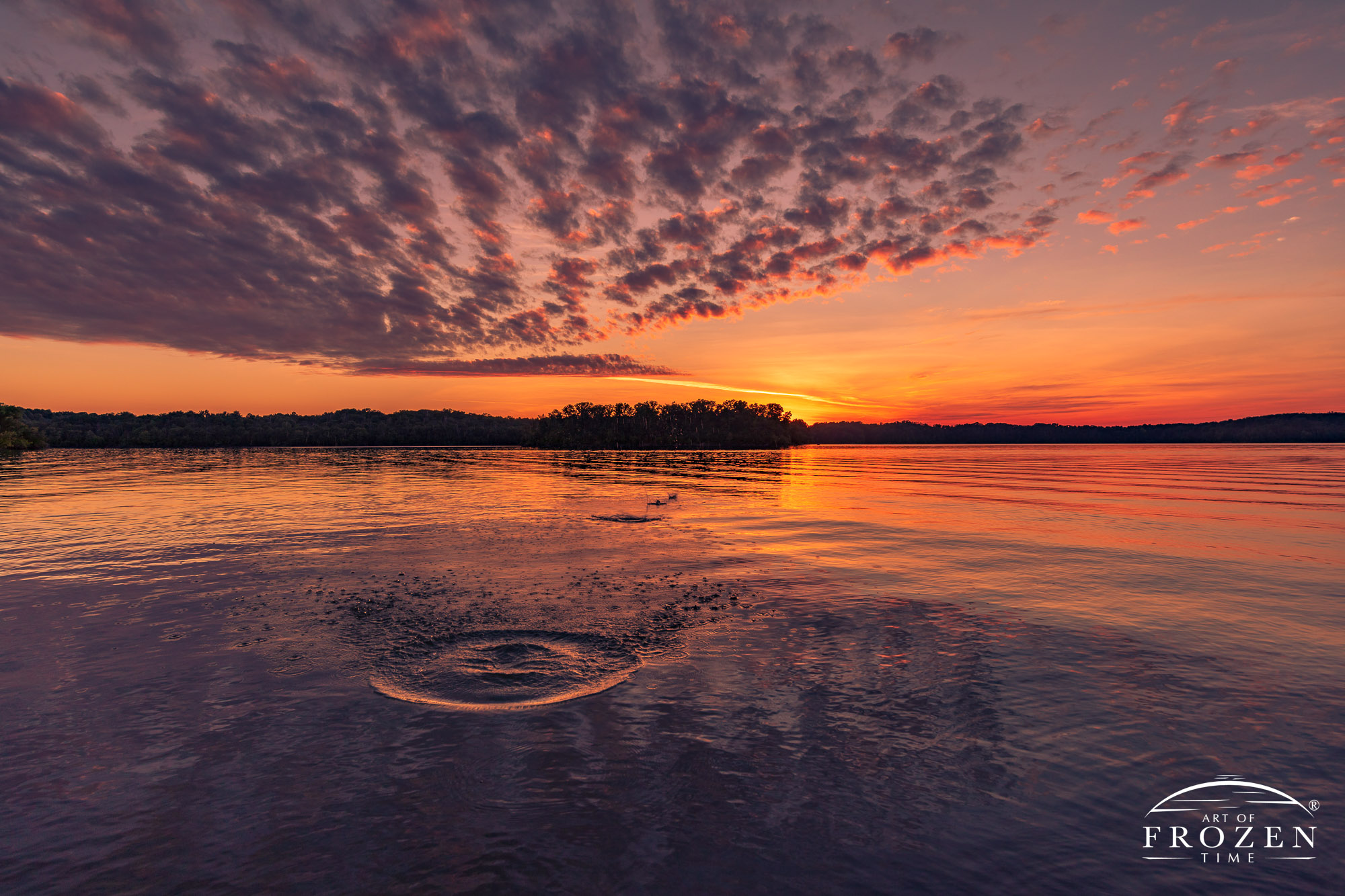 A skipped-rock forms series of concentric circles leading the eye into the colorful sunset