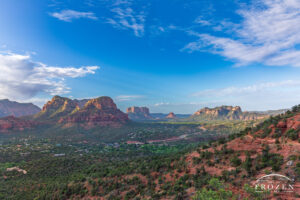 A wide-angle view of Sedona Valley at sunrise where Arizona State Route 179 winds through the valley below the city's famous red rock formations as the morning light paints the scene in warm light