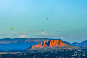 Three hot air balloons during a morning flight over Sedona where the warm light washes over the red rock formations