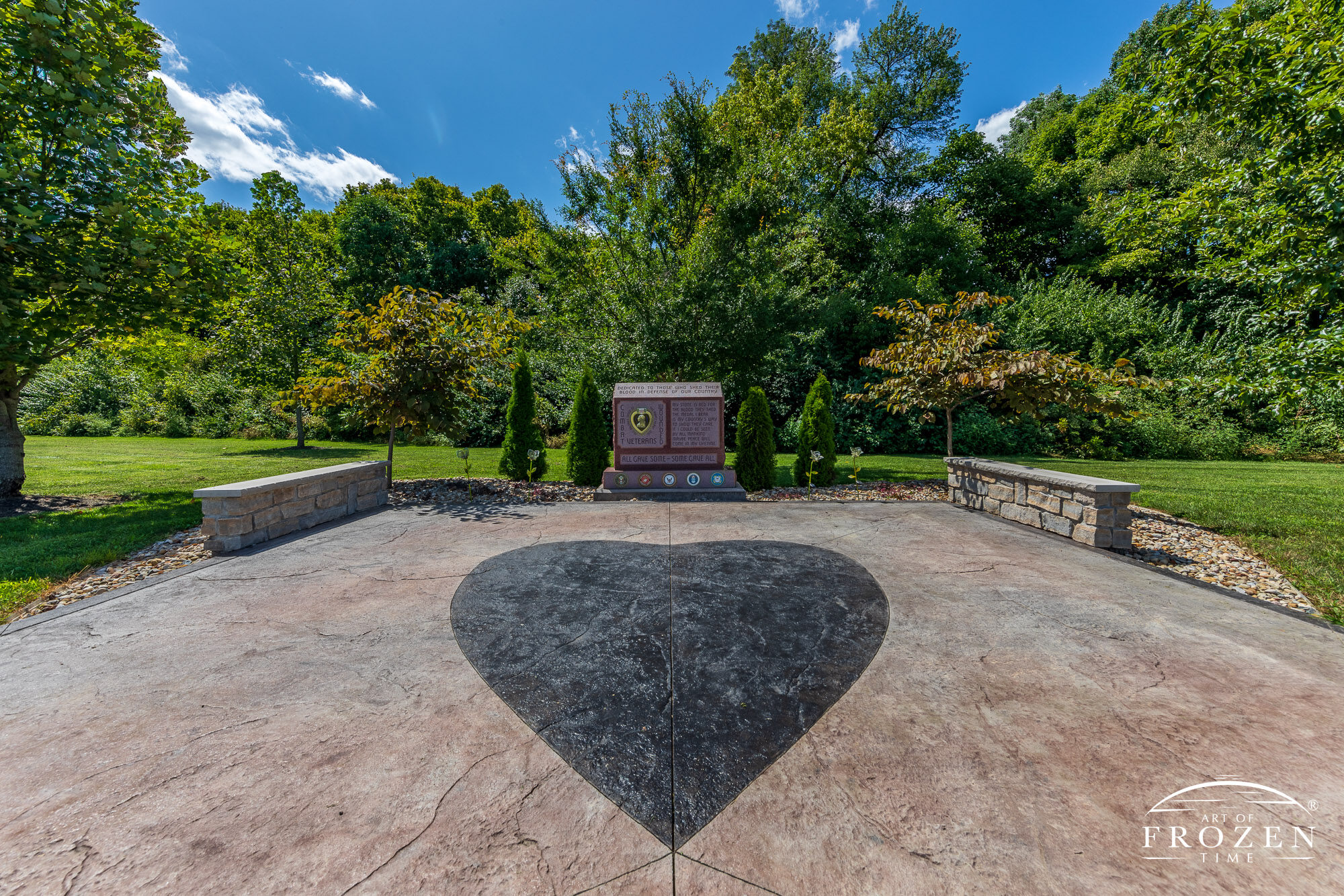 A view of Springboro Ohio’s Purple Heart memorial where designers placed a large heart in stamped concrete to the foreground of the city’s granite memorial