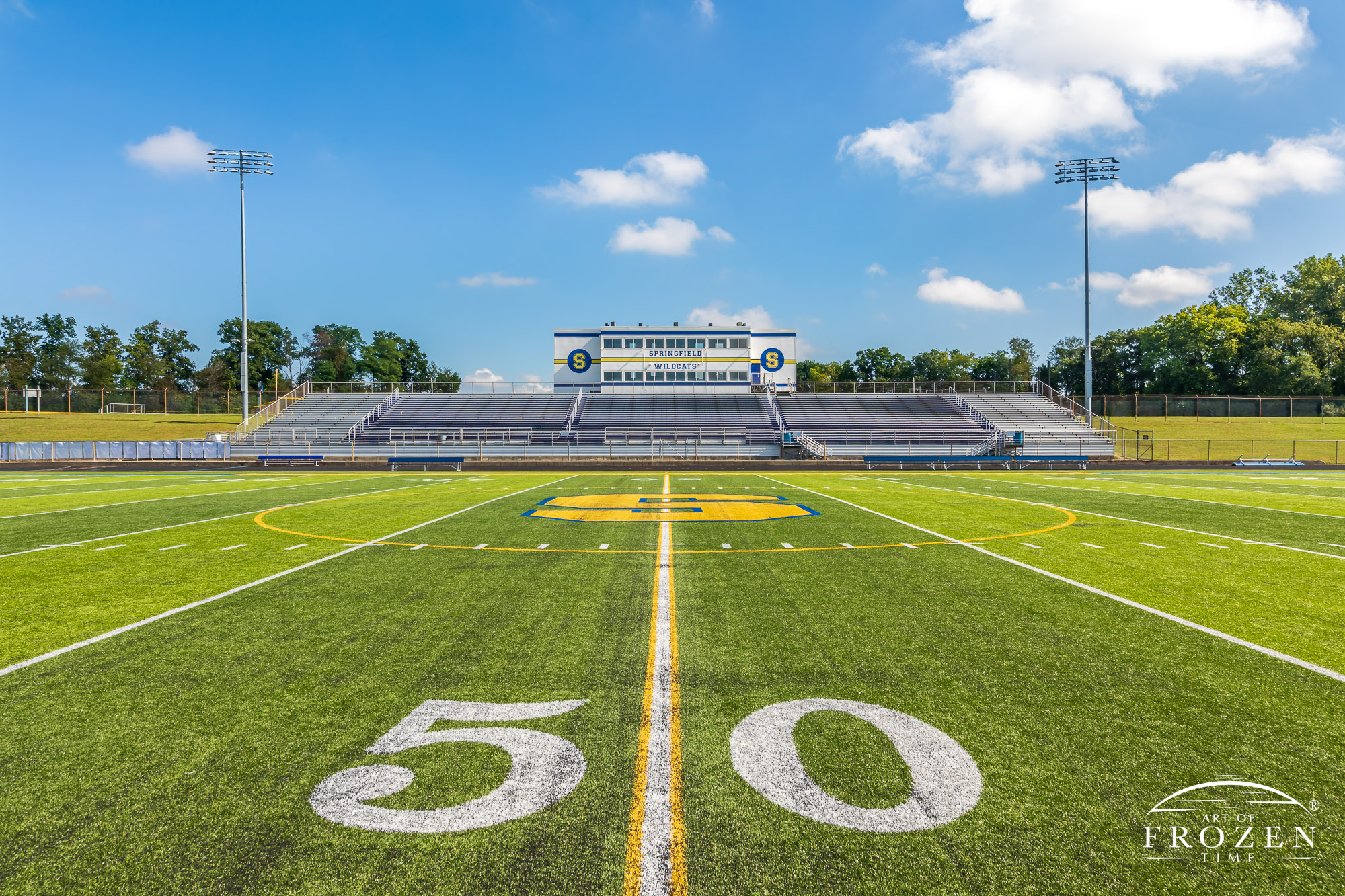 Wide angle views of Springfield Wildcat Stadium on a sunny day featuring artificial turf and the school’s blue and yellow colors.