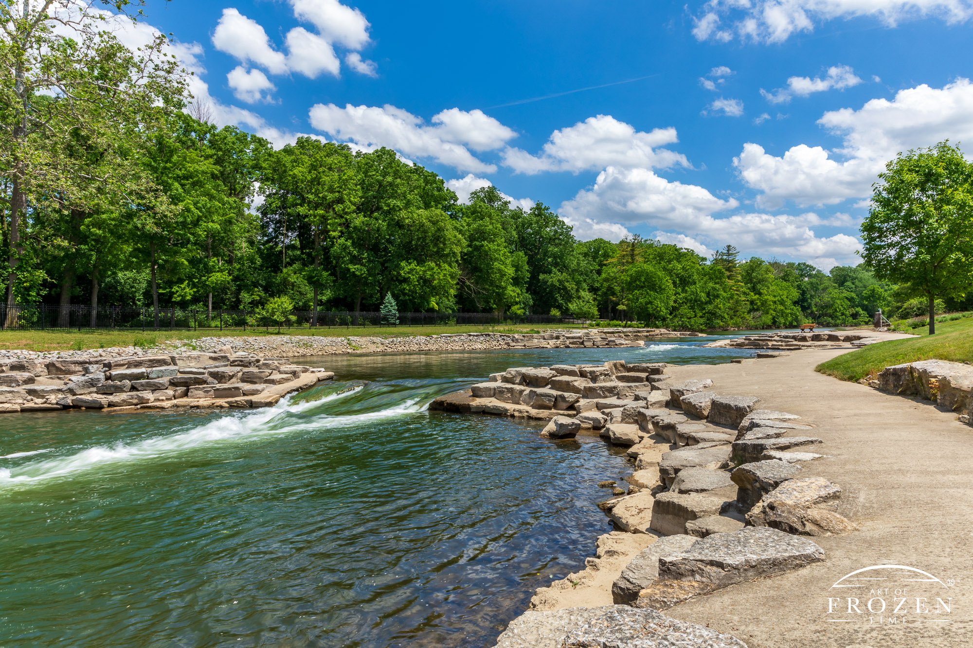 A whitewater play area in downtown Springfield Ohio where Buck Creek flows by under blue skies and cumulus clouds