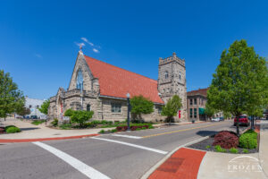 St. James Episcopal Church in Piqua Ohio which features a full stone exteriors and a terra cotta roof under one of the blue skies over Miami County