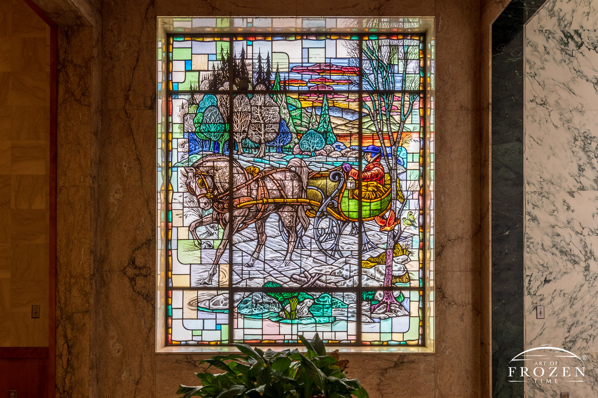 Historic stained-glass windows created by Louis Comfort Tiffany featuring his opalescent glass depicting a horse-draw sleigh by a forest under a colorful sunset