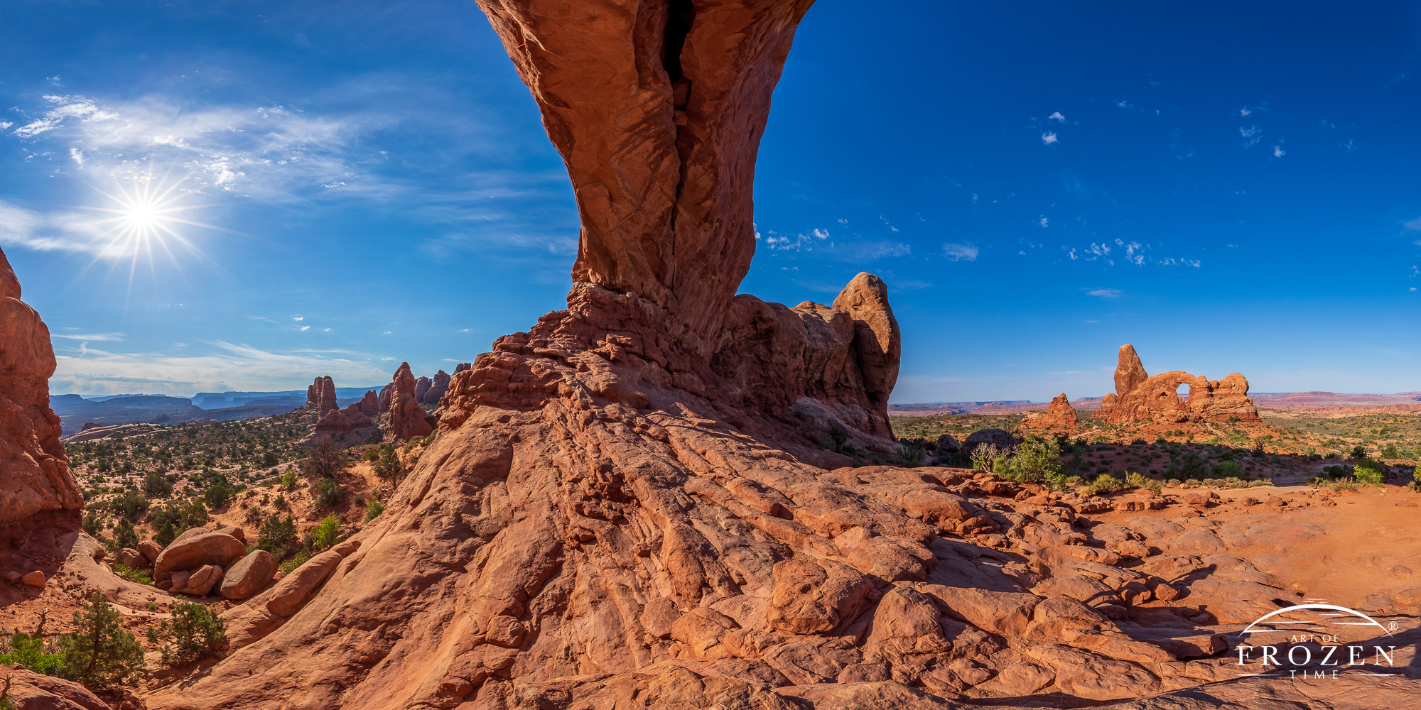 A panoramic sunrise from Arches National Park where the North Window arches to the center of the image and Turret Arch basks in the morning light