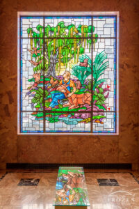 Stained-glass window in Woodland Mausoleum depicting a young man holding a deer beneath a moss-covered oak tree surrounded by woodland animals in Dayton Ohio