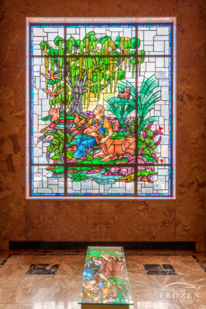 Stained-glass window in Woodland Mausoleum depicting a young man holding a deer beneath a moss-covered oak tree surrounded by woodland animals in Dayton Ohio