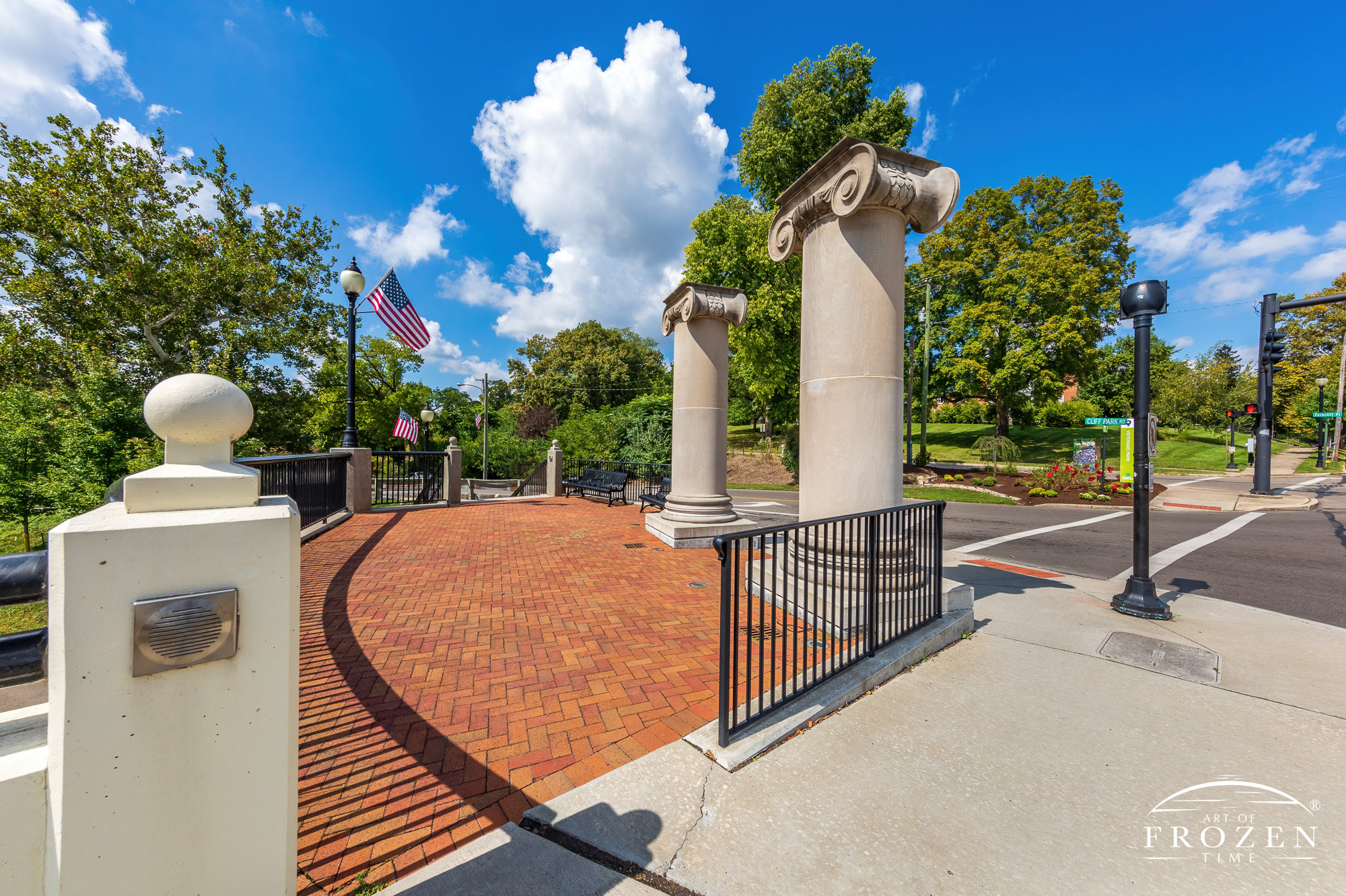 A pair of smooth columns with decorative scroll tops stand on a corner in Springfield Ohio marking the entrance to the Veterans Park Memorial.