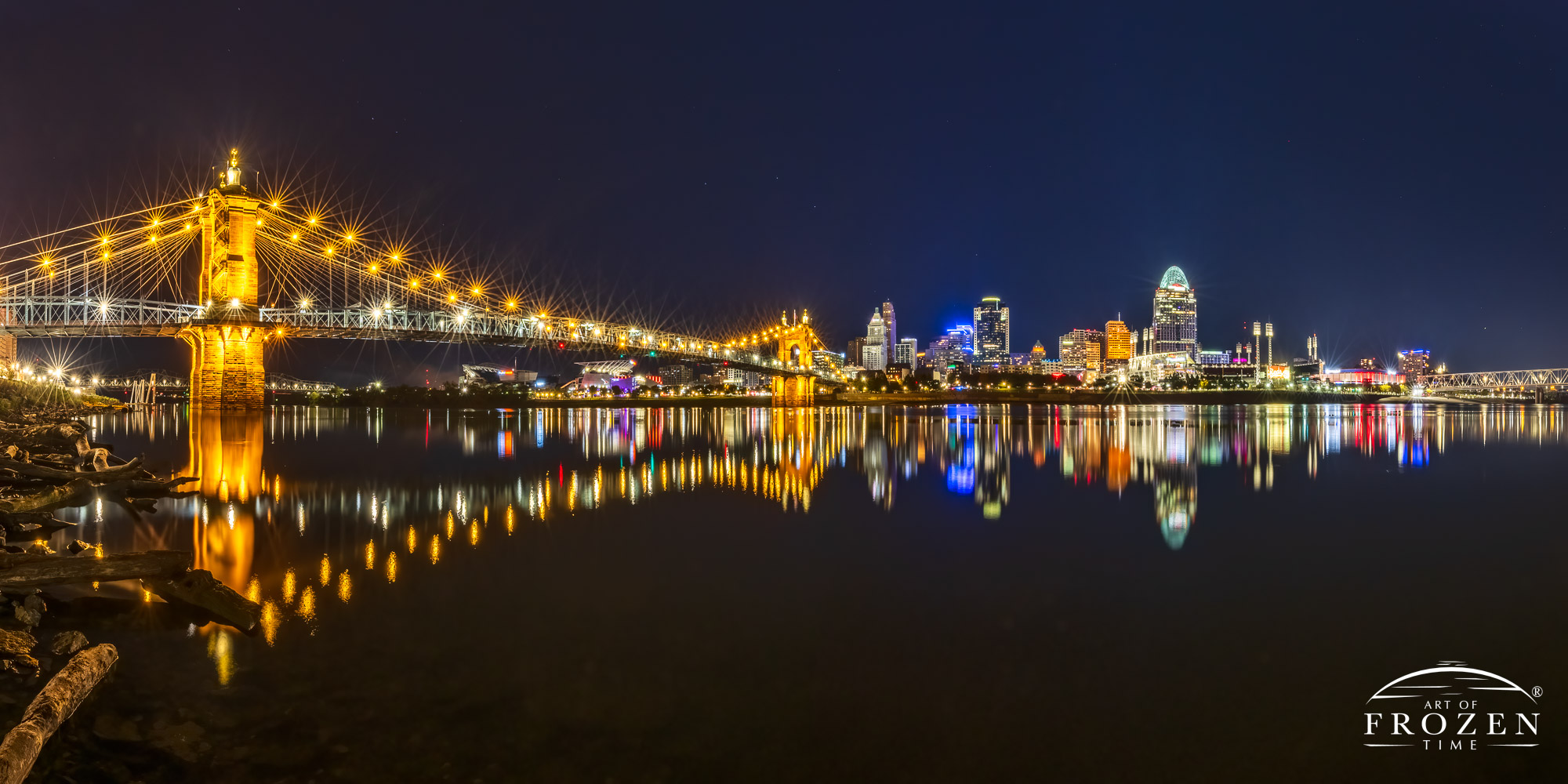 Cincinnati Fine Art photography panorama where the Roebling Bridge leads the eye across the Ohio River towards the Cincinnati Skyline during a peaceful evening