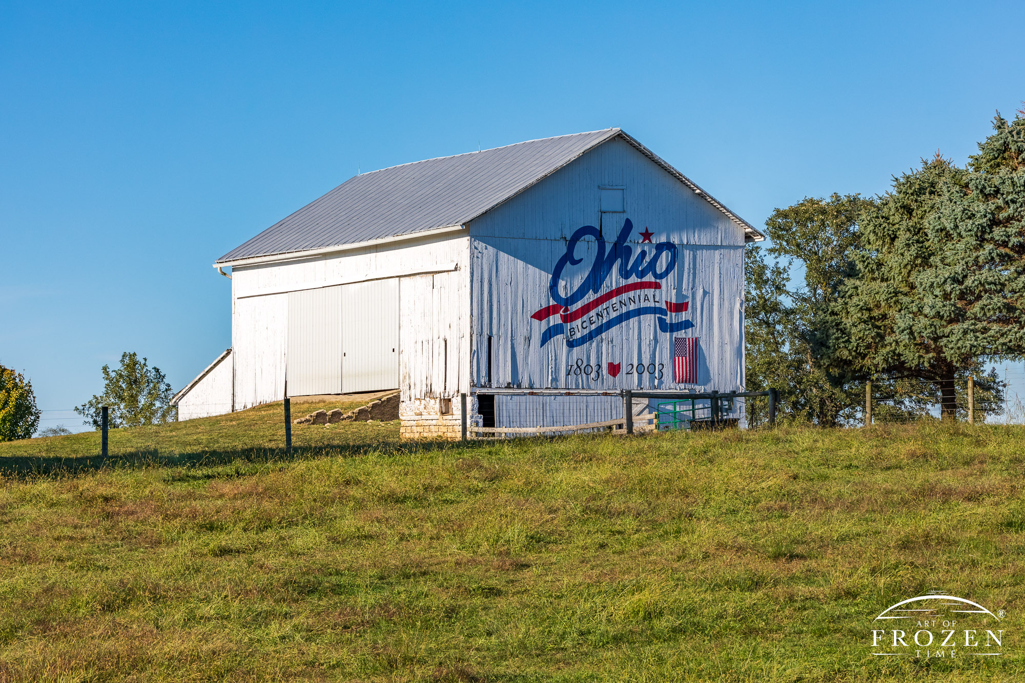 The Greene County Bicentennial Barn with its red, white, and blue logo as the setting sun paints it in golden light