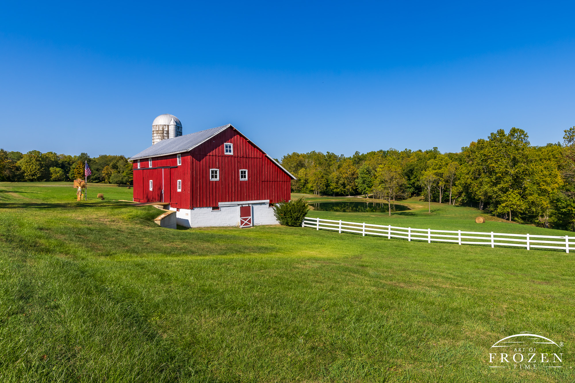 A picturesque Greene County, Ohio, barn on a stunning evening, where the red and white structure contrasts beautifully with the deep blue sky and vibrant green grass.