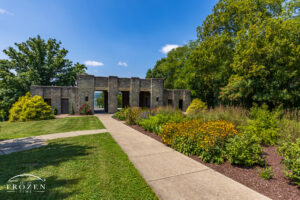 A pathway the leads the eye along a garden towards the Mt. Storm Park stone pavilion on a pretty summer day