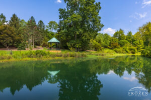 A lake side gazebo at Mt Airy where the water reflects the peaceful shoreline on a summer day