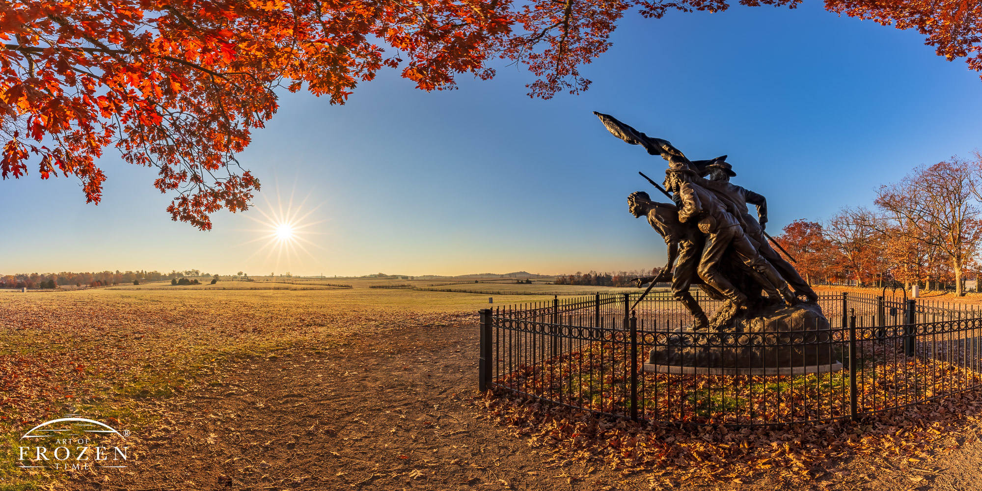 An autumn morning panorama of the North Carolina State Monument at Gettysburg, where the golden light backlights the red oak leaves.