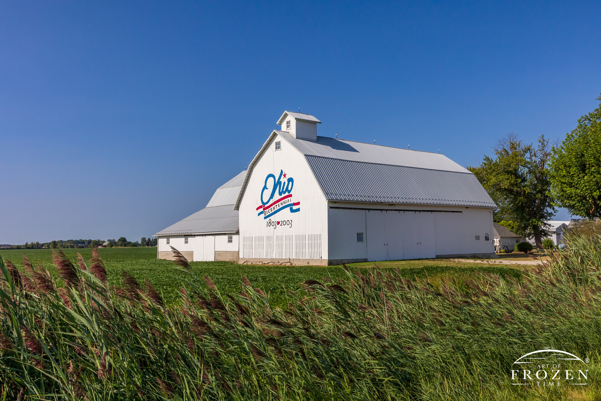 An Ohio Cultural landmark and the Ottawa County Bicentennial Barn, an unusually large white barn displaying the red, white and blue logo on blue Ohio skies.