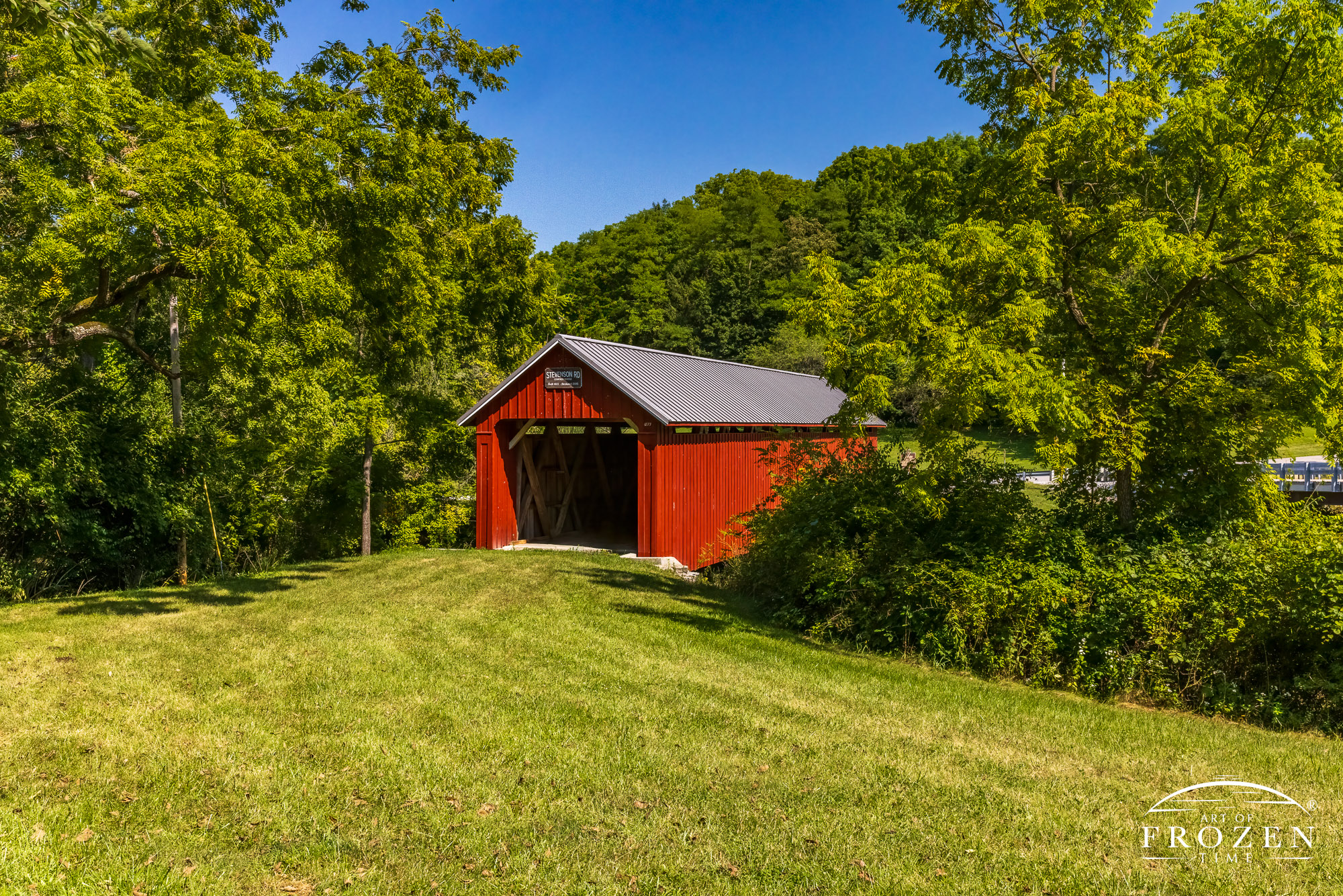 Stevenson Road Covered Bridge northeast of Xenia where the blue skies, green vegetation and bright red pain perfectly contrast on a summer day, capturing another example of an Ohio Covered Bridge