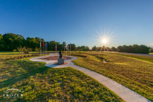 Sugarcreek Township Veterans Memorial Sunrise at Golden Hour No | Art of Frozen Time Sugarcreek Veterans Memorial in Bellbrook Ohio with Sunstar, long shadows, flags, and Pee Wee Martin statue in clear blue morning sky
