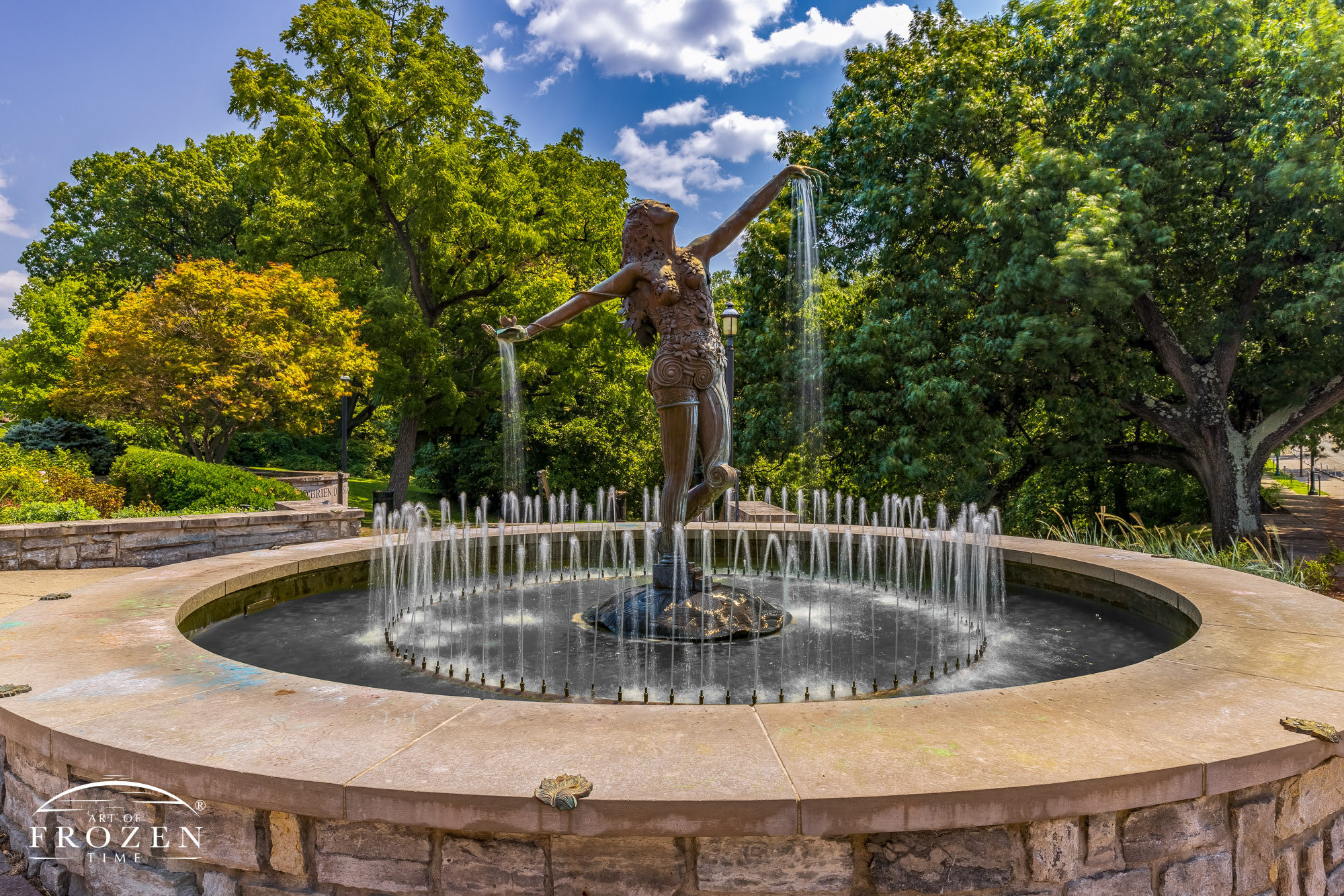 A graceful sculpture titled the Muse of Clifton stands in Burnet Woods on a summer day where water streams from her open palms.