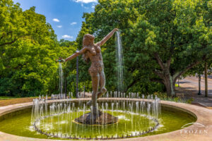 A graceful sculpture titled the Muse of Clifton stands in Burnet Woods on a summer day where water streams from her open palms.